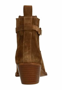 Stivaletto in suede marrone con tacco a blocco, dotato di una fascia laterale e dettaglio con fibbia, due cuciture verticali e una texture morbida.