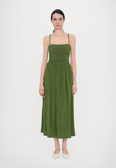 Lungo vestito verde con spalline sottili, corpino arricciato e gonna fluida. Realizzato in tessuto leggero, presenta una superficie liscia e una vestibilità comoda.