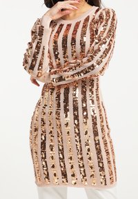 Långärmad stickad klänning med växlande ränder av rosaguld och bronspaljetter på en mjuk beige bas, med en avslappnad passform.