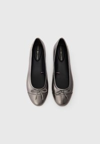 Metallic gray ballet flats with a rounded toe, decorative bow detail, and a smooth texture. Black insole with branding visible.
