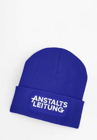 Blue knit beanie featuring a folded cuff and a rectangular patch with the text “ANSTALTSLEITUNG” in bold white letters.