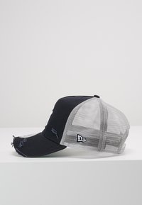 Schwarze Baseballkappe aus strukturiertem Stoff, grauer Netzrücken, gebogener Schirm, Logodetail an der Seite und sichtbare Nähte.