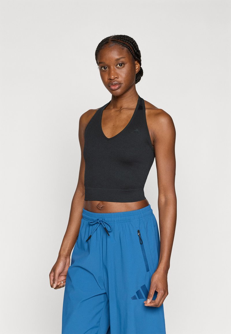 Haut de sport noir court avec un design en col en V, présentant une silhouette ajustée et de larges bretelles halter. Associé à un short bleu à cordon de serrage.