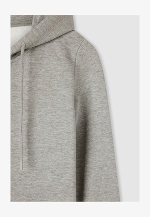 Felpa grigia con un tessuto morbido e testurizzato. Presenta un cappuccio con coulisse e orlo a coste. La vista ravvicinata mette in evidenza le cuciture e la qualità del materiale.