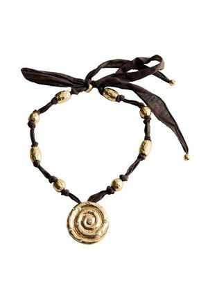 Collier en tissu marron avec des perles dorées et un grand pendentif circulaire en or avec un motif en spirale et de petites pierres précieuses incrustées.