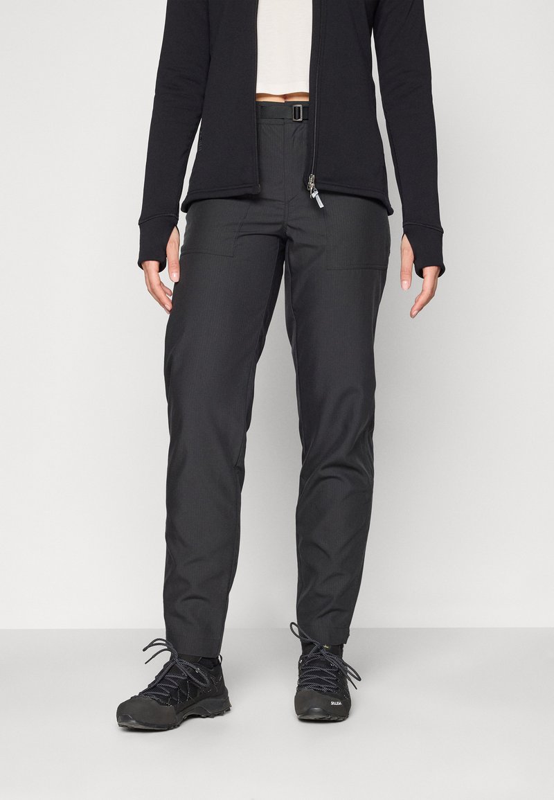 Svart teknisk bukse med slim fit, med sidelommer, teksturert stoff og en sikker beltesløyfe. Kombinert med tursko.
