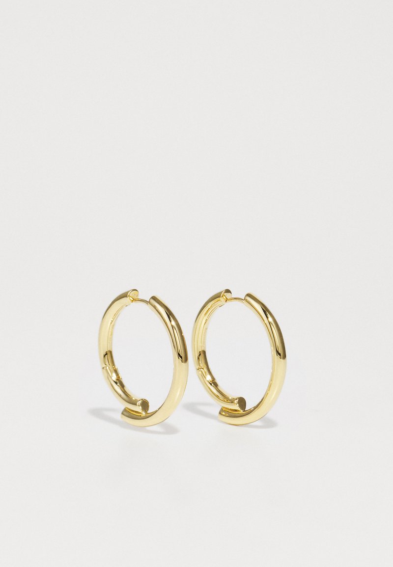 Goldene Creolen mit polierter Oberfläche, kreisförmiger Form und einem sicheren Verschluss. Jedes Ohrstecker hat ein glattes, nahtloses Design.