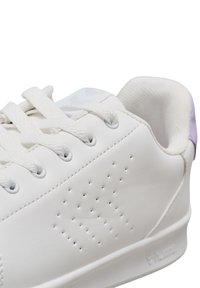 Baskets en cuir blanc avec surface texturée, bout rond et accents perforés. Dotées de lacets blancs et d'un tirant de talon lilas.