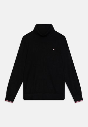 Pull à col roulé noir en tissu tricoté, avec des manches longues, des poignets côtelés et un petit logo sur la poitrine. Accents rouge et blanc au niveau des poignets.
