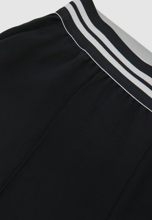 Juodi sportiniai šortai su pilkų ir baltų dryžuotų elastingų juosmenų dirželiu. Lygios audinio tekstūros su šoninėmis siūlių detalėmis.