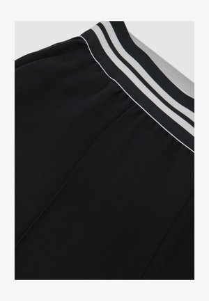 Juodi sportiniai šortai su pilkų ir baltų dryžuotų elastingų juosmenų dirželiu. Lygios audinio tekstūros su šoninėmis siūlių detalėmis.