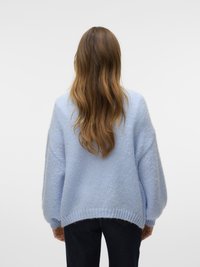 Ανοιχτό μπλε oversized πουλόβερ φτιαγμένο από μαλακό, υδροχρώμα υλικό. Διαθέτει χαλαρούς ώμους και ριμπ μανίκια, συνδυασμένο με σκούρο τζιν παντελόνι.