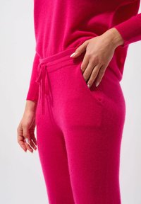 Fuchsia gebreid loungewear set met een aansluitende trui en jogpants met koordjes en zijzakken, met een zachte textuur en een ontspannen silhouet.