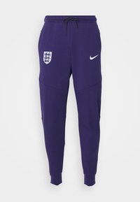 Lila Nike-joggingbyxor med elastiskt midjeband, justerbar dragsko, avsmalnande mudd, sidofickor och Englands emblem på vänster lår.