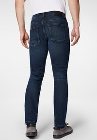 Ciemnoniebieskie jeansy o dopasowanym kroju, charakteryzujące się gładką teksturą, pięcioma kieszeniami oraz markową skórzaną naszywką na pasku.