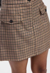 Gonna a motivo houndstooth marrone e beige con due tasche laterali, bottoni neri e un design strutturato, realizzata in tessuto testurizzato.