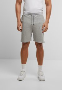 Grijze katoenen sportshorts met een elastische tailleband en trekkoord. Gecombineerd met witte sneakers en korte sokken.