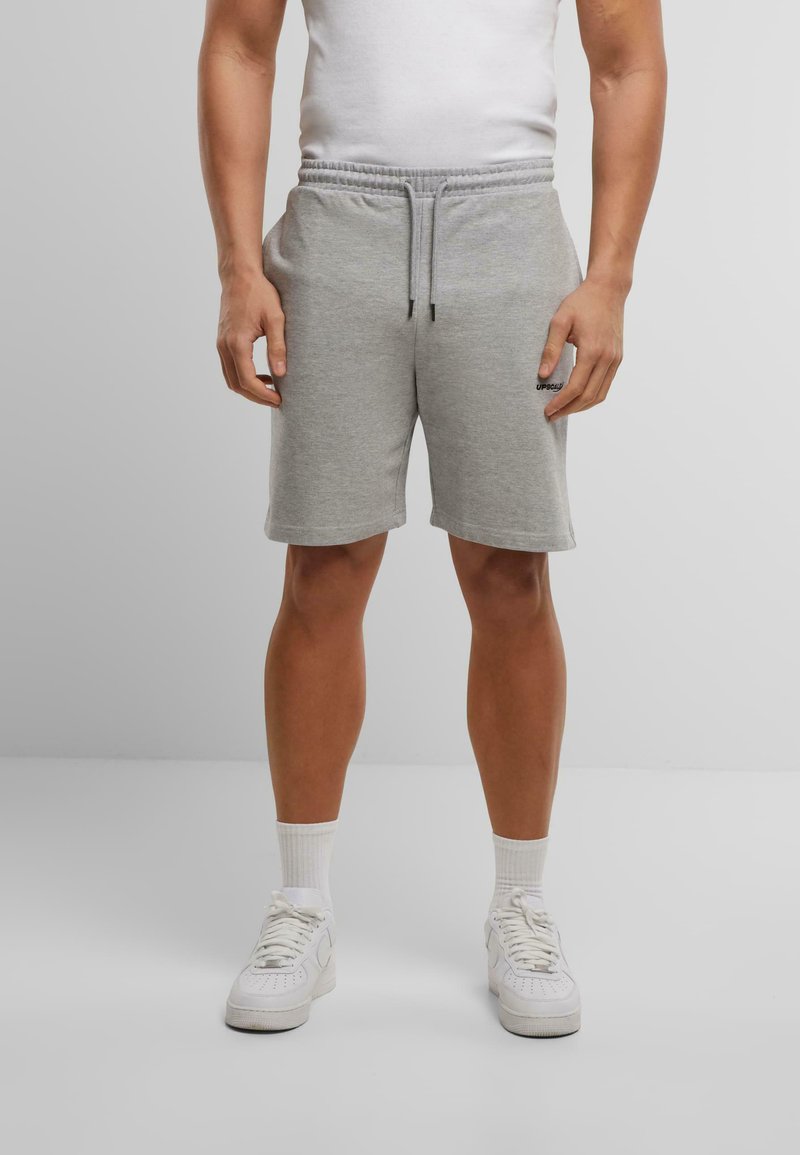Grijze katoenen sportshorts met een elastische tailleband en trekkoord. Gecombineerd met witte sneakers en korte sokken.