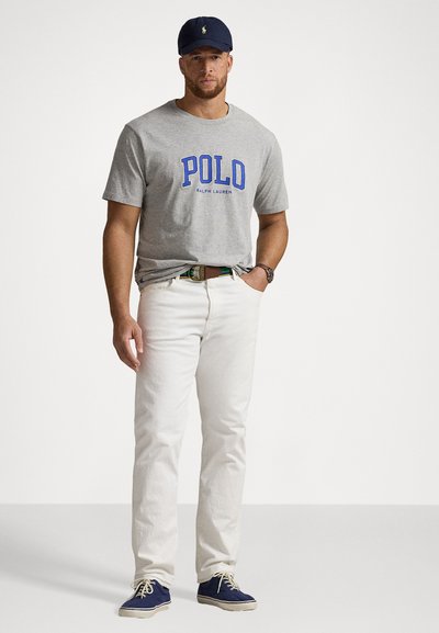 Pelēka kokvilnas T-kreklu ar zilu "POLO" logo, baltas džinsus un tumši zilus kanvas apavus. Aksesuāri ietver saskaņotu tumši zilu cepuri un daudzkrāsainu jostu.