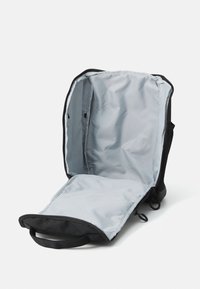 Black backpack with light gray interior fully unzipped and open, showing spacious main compartment and two zipper pulls.