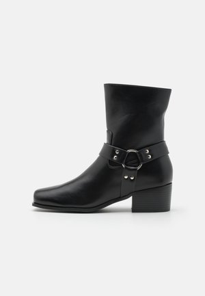 Mustad mustad mustad neidade nahast, ruudukujulise varbaga, laia rihmaga ja ringikujulise detailiga, samuti tugeva virnastatud kontsaga.