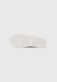Semelle de chaussure en caoutchouc blanc avec des rainures horizontales et des motifs texturés pour une meilleure adhérence. Présente un design minimaliste et une couleur claire.