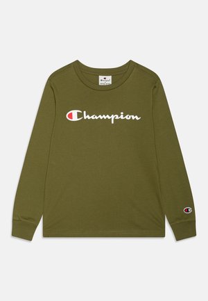 Chemise à manches longues vert olive avec logo Champion blanc et rouge sur la poitrine et petite écusson logo sur le poignet gauche.