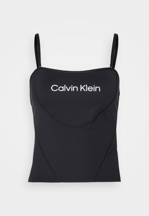 Sort tætsiddende camisoletop med tynde stropper og "Calvin Klein"-logo i hvidt centreret på brystet mod en ensfarvet baggrund.