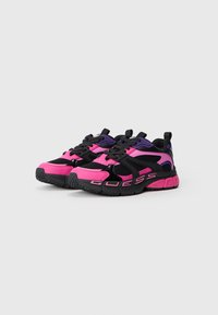 Sportssko med rosa og svart design, med mesh- og syntetisk overdel, tykk såle og fremtredende "GUESS"-merke på siden.