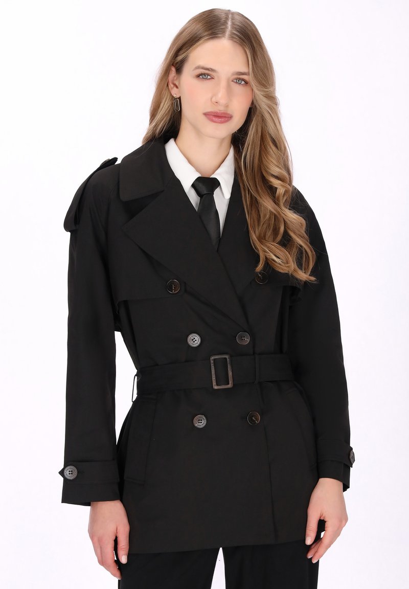 Fekete kétsoros ballonkabát nagy gombokkal, öves derékrésszel és vállapokkal. Fehér inggel és fekete nyakkendővel kiegészítve.