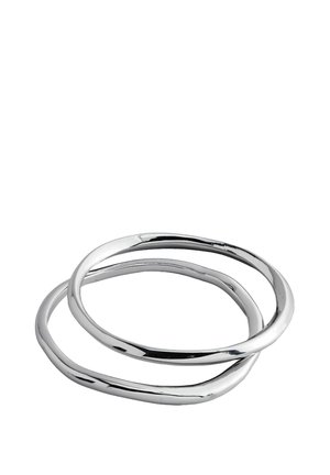 Zwei ineinandergreifende Ringe aus poliertem Silbermetall. Das Design zeichnet sich durch glatte, geschwungene Kanten mit einer durchgehenden, fließenden Form aus.