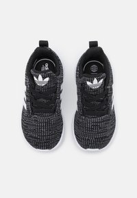 Scarpe sportive nere con tomaia in maglia testurizzata, design con tre strisce bianche e lacci neri. Presentano un colletto imbottito e un logo sulla linguetta.