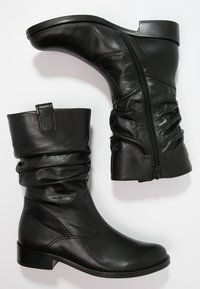 Czarne skórzane botki za kostkę z luźnym fasonem i bocznym zamkiem błyskawicznym. Posiadają okrągły nosek i niski, klepany obcas. Gładka tekstura na całej powierzchni.