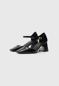 Schwarze patentierte Leder-Pumps mit quadrater Zehenpartie, Fesselriemen und strukturiertem Krokodilmuster; mit Blockabsatz-Design.