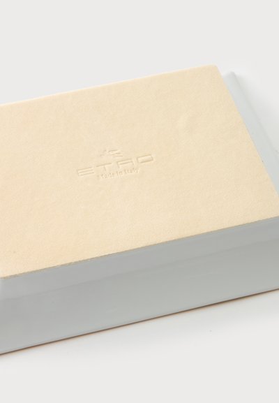 Boîte rectangulaire beige avec le logo "ETRO Made in Italy" embossé sur le dessus, posée sur une surface lisse gris clair.
