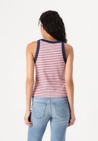 Raudonai ir baltais juostuotas tanktopas su tamsiai mėlynu apvadu, matomas iš nugaros. Pagamintas iš medvilnės, turi prigludusią struktūrą, derinamas su šviesiai mėlynomis džinsomis.