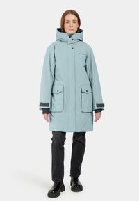 Ljusblå vattentät parka med huva, stora framfickor och svarta detaljer. Minimalistisk design, hållbart material och avslappnad passform.