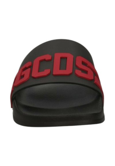 Sandalo con suola nera e spesse lettere rosse "GCDS" sulla cinghia superiore, mostrato da un angolo frontale.