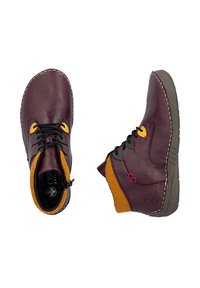 Paire de bottines en cuir violet avec des lacets noirs, des œillets jaunes et des poignets en tricot orange, vues de dessus et de côté.