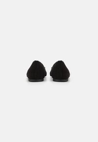 Svarta mocka loafers med rund tå och minimal klack. Har en slät yta och en enkel, elegant design utan utsmyckningar.