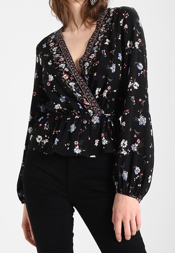 Blusa avvolgente nera a fiori con maniche lunghe a sbuffo, scollatura a V e vita elastica. Presenta motivi floreali blu, rossi e bianchi e un bordo decorativo.