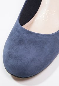 Gros plan sur une chaussure ballerine femme en suède bleu marine, avec un bout arrondi et une doublure intérieure beige.