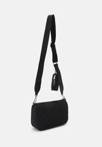 Svart vadderad axelremsväska i mjukt material, med avtagbar rem och en liten dragkedjeficka fäst. Silverfärgade detaljer.