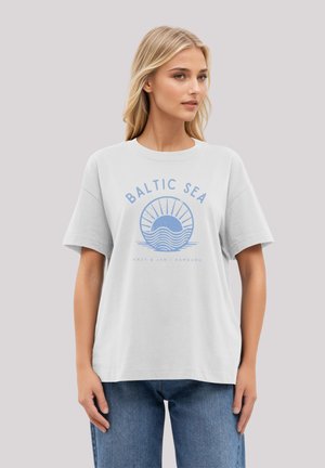White cotton t-shirt with short sleeves featuring a blue graphic design of waves and sun. Text reads "BALTIC SEA," with additional details below.