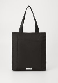 Borsa tote nera realizzata in tessuto resistente, con lati piatti, doppi manici e un'etichetta con il logo sulla parte frontale. Design pulito e texture semplice.
