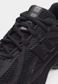 Čierna bežecká obuv New Balance s textúrovaným sieťovaným zvrškom, prekríženými šnúrkami a výrazným bočným logom "N".