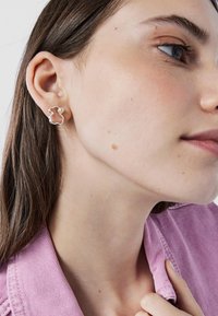 Orecchini d'argento a forma di silhouette di orso con un piccolo accento di perla. Il design presenta curve morbide e una finitura lucida.