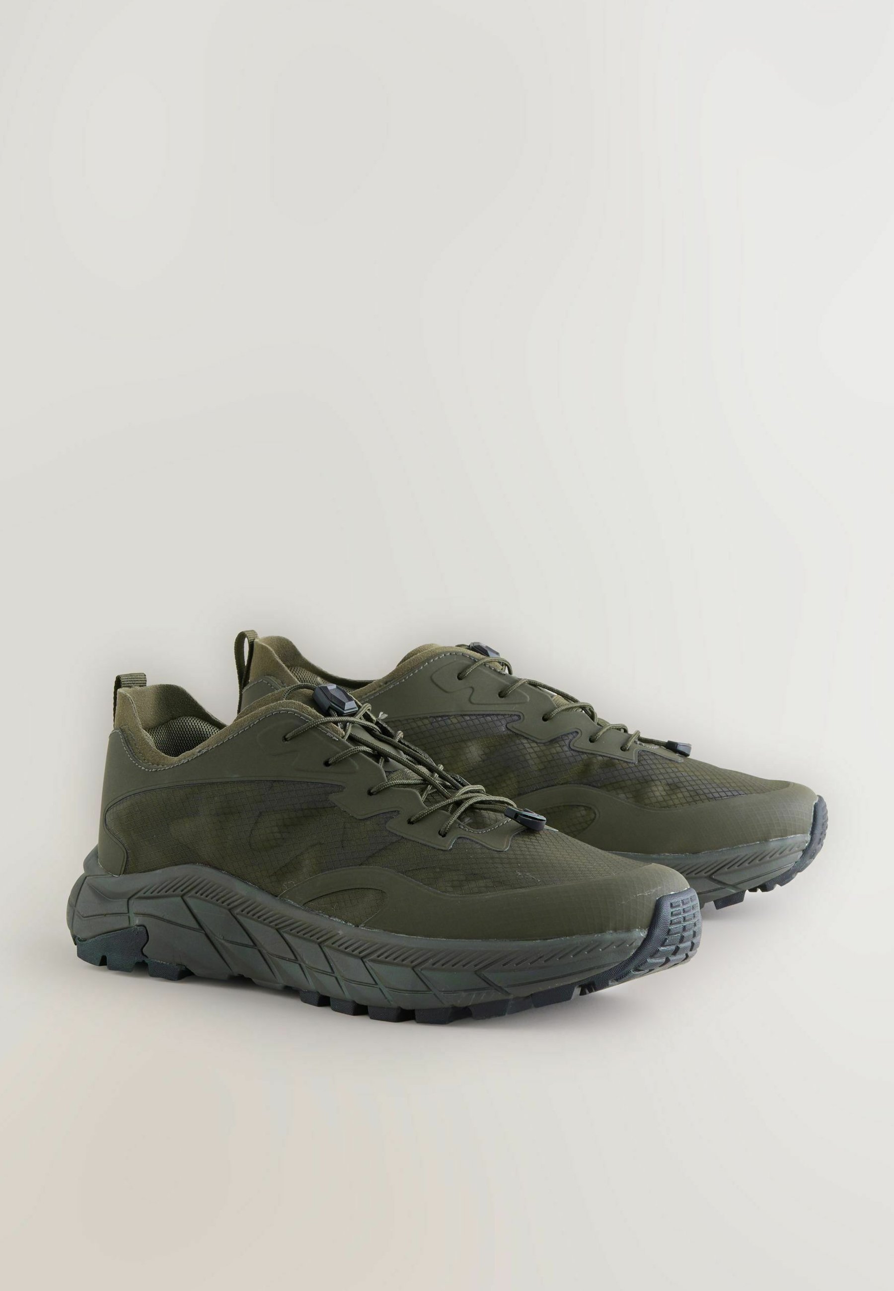 Green athletic shoes with a textured mesh upper, rubber sole, and padded collar. Features a secured lace system for adjustable fit.