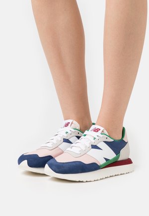 Marineblauwe en lichtroze sneakers met suède en leer, witte accenten, groene details en een rood hielstuk. Klassiek atletisch ontwerp.