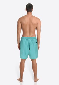 Turquoise zwembroek met een elastische tailleband, knielengte, voorzien van een achterzak. Gladde textuur, lichtgewicht materiaal, minimalistisch ontwerp.
